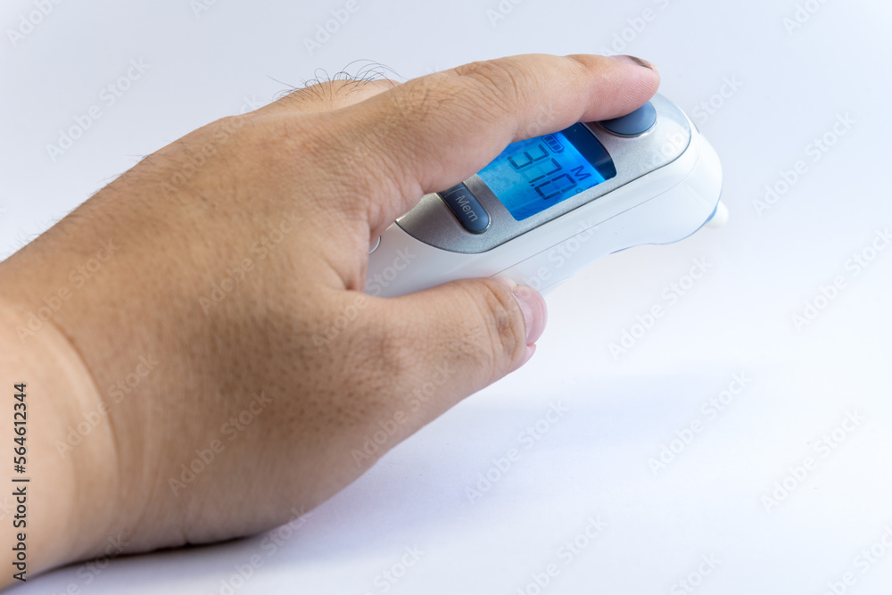 Human hand hold a digital infrared thermometer for body temperature scan from Coronavirus disease COVID-19, flu, fever or other sickness. Health care concept. Human hand hold a digital infrared thermometer for body temperature scan from Coronavirus disease COVID-19, flu, fever or other sickness. Health care concept.