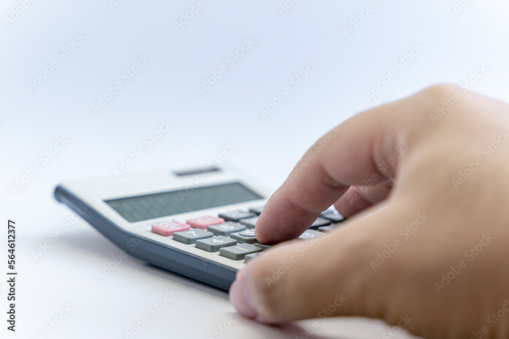 Hand calculating with a white digital calculator isolated on white background. Calculator with Solar and battery function. Business, financial, accounting concept. Hand calculating with a white digital calculator isolated on white background. Calculator with Solar and battery function. Business, financial, accounting concept.