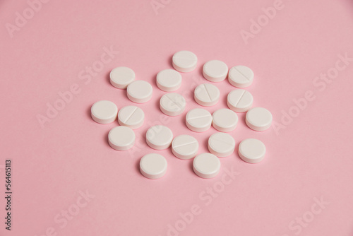 Flatlay, many white pills on a pink paper background