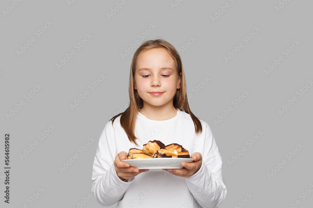 Happy smiling child girl eating dessert against grey studio wall background Happy smiling child girl eating dessert against grey studio wall background