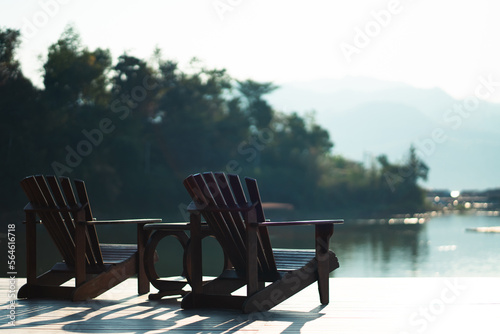 Classic wooden tables and chairs for relaxing by the resort's waterfront in the morning sunlight