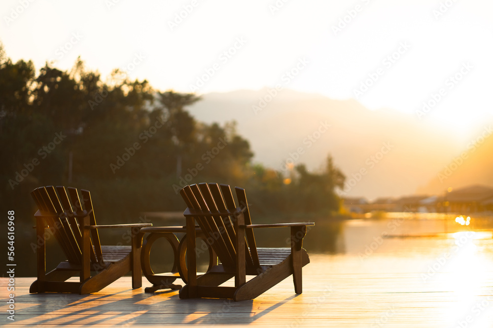Fototapeta premium Classic wooden tables and chairs for relaxing by the resort's waterfront in the evening sun