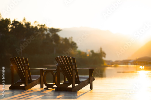 Classic wooden tables and chairs for relaxing by the resort's waterfront in the evening sun