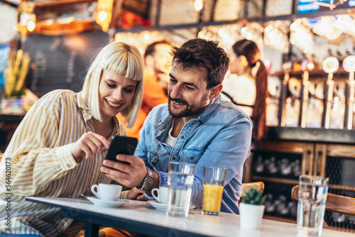 Young happy couple using smartphone in cafe