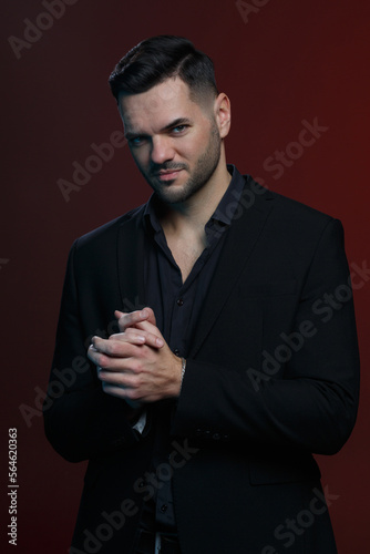 Attractive man in an elegant black suit  on a dark burgundy background. © ksi