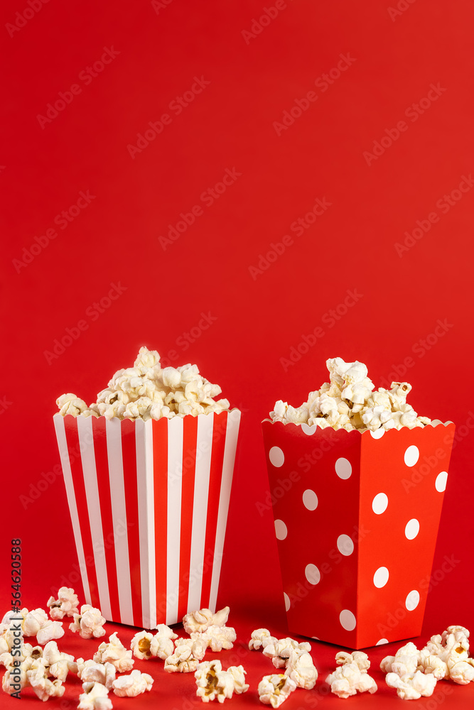 two bags of popcorn in red and white on a red background, front view, copy space