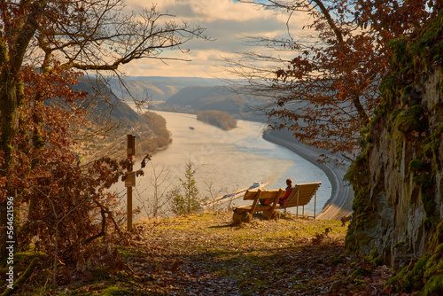 Mädchen sitz auf Bank und schaut sich den Rhein an im Spätsommer photo