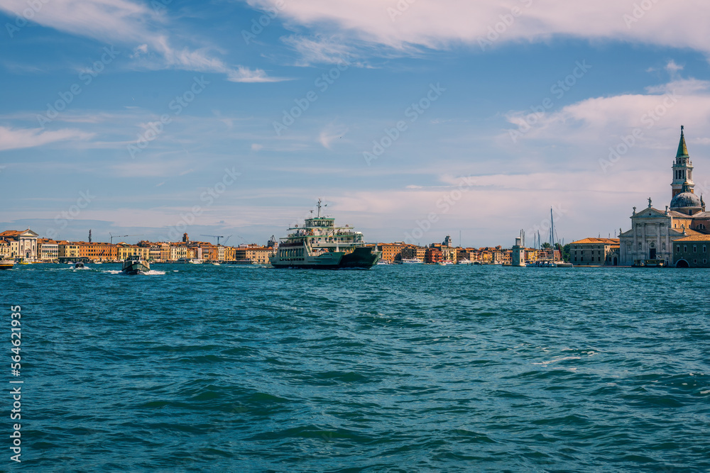 Ships with tourists at sea in the Venetian Bay against the backdrop of ancient houses on the Grand Canal, a beautiful view from the water on a sunny day to Venice, vacation and travel in Italy