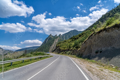 Asphalt serpentine road turn in mountainous landscape with fluffy clouds on sky in Dagestan, Russia.