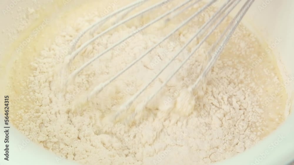 Beating the pancake dough with a whisk in a mixing bowl, mixing flour with eggs, close up slow motion video, high quality 4k footage. High quality FullHD footage Beating the pancake dough with a whisk in a mixing bowl, mixing flour with eggs, close up slow motion video, high quality 4k footage. High quality FullHD footage
