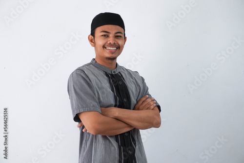 smile or happy young asian muslim man crossed arms and looking camera wearing grey koko clothes isolated on white background photo