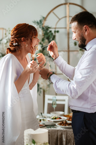 newlyweds happily cut and taste the wedding cake