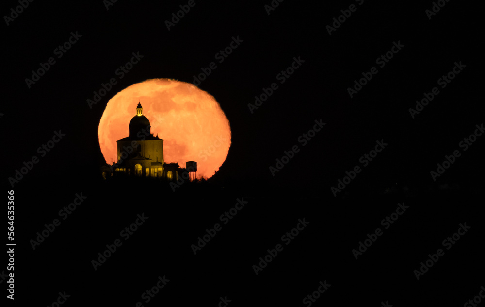 Church silhouette against a big orange full moon
