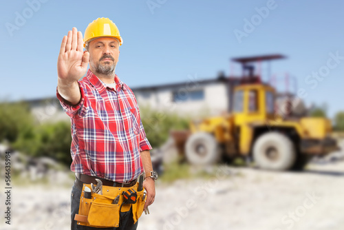 Bossy man showing stop gesture in front of machinery