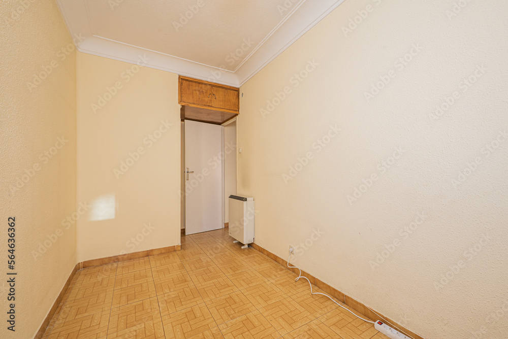 Small empty room with plain cream painted walls with gotelet , ugly tile floor and cheap white wooden door Small empty room with plain cream painted walls with gotelet , ugly tile floor and cheap white wooden door