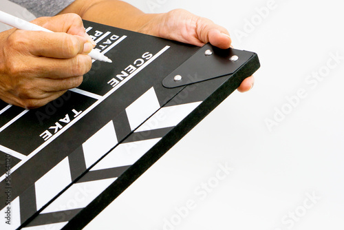 The hand is holding clapperboard or movie slate black color and marker pen. Cinema industry concept.
