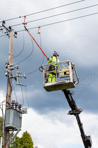Electric worker in truck bucket near pole