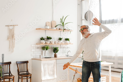 Happy senior man dancing while listening to music with headphones - active old people and enjoyment dance mood