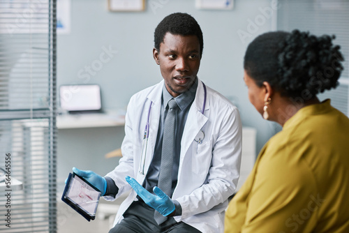 Young medical professional talking to patient in clinic