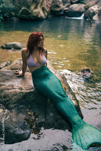 Sirena pelirroja en una gruta rio con agua encantado manantial misterioso en bosque frondoso y verde