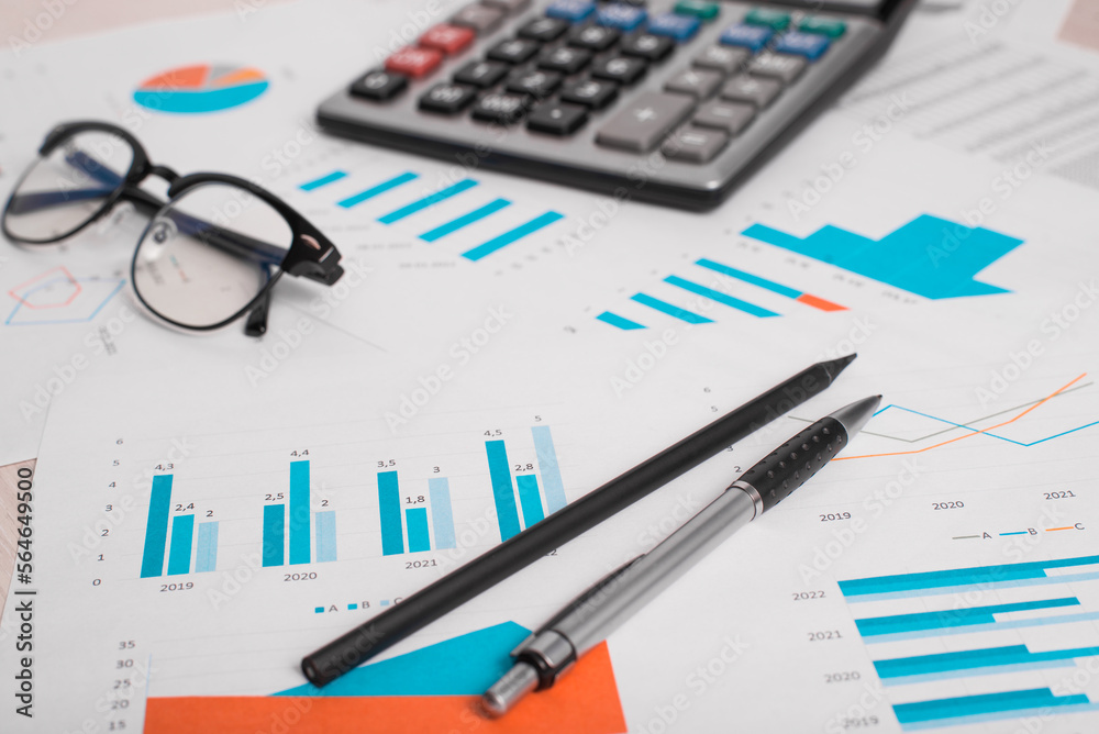 Workplace, calculator, glasses and financial documents on desktop. Accounting and business. Close-up, selective focus, low angle view Workplace, calculator, glasses and financial documents on desktop. Accounting and business. Close-up, selective focus, low angle view