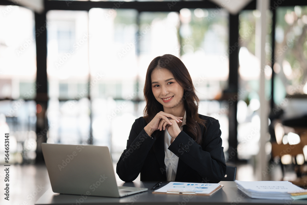 Happy smiling Asian businesswoman working and looking at the camera in office room.