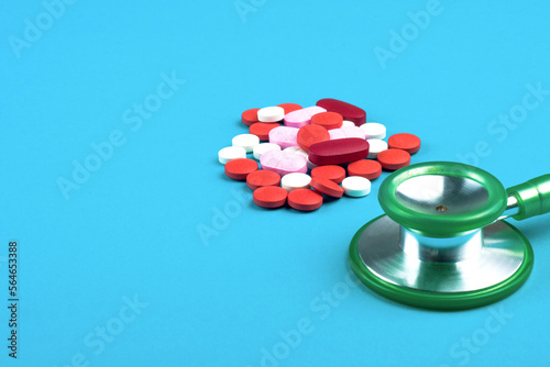 Pills color red, pink, white, and stethoscope green with blue background