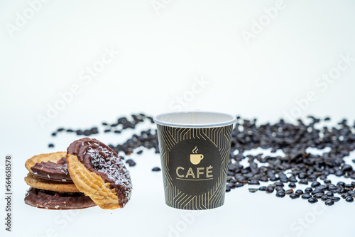 galletas de coco y chocolate sobre fondo blanco con un baso de cake para desayunar, granos de cafe caidos photo