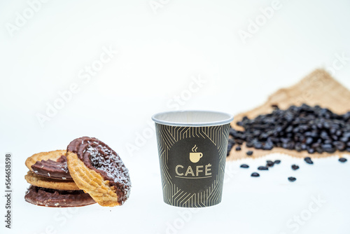 galletas de coco y chocolate sobre fondo blanco con un baso de cake para desayunar, granos de cafe caidos photo
