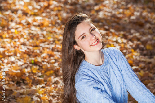 Portrait of a young girl in blue sweater, autumn park outdoor