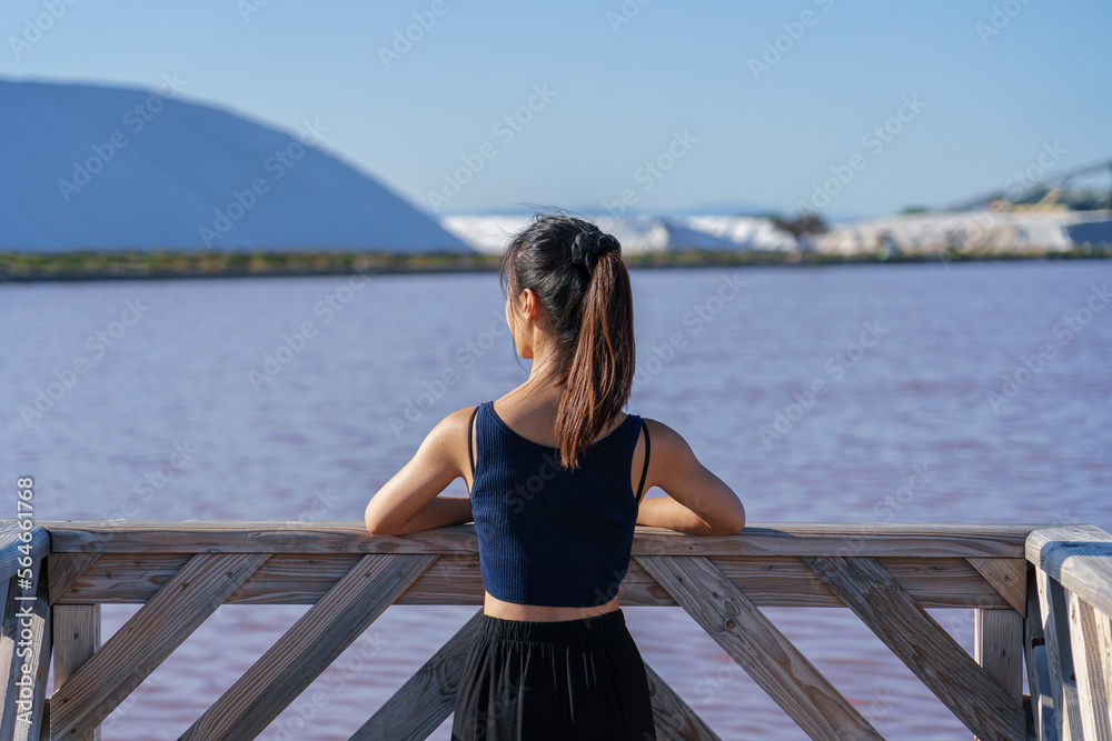 Woman wearing a sports vest at Salin d’Aigues-Mortes with pink salt lake in the background