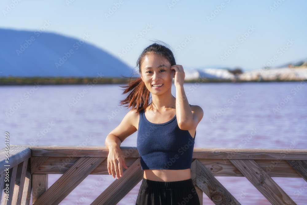 Woman wearing a sports vest at Salin d’Aigues-Mortes with pink salt lake in the background