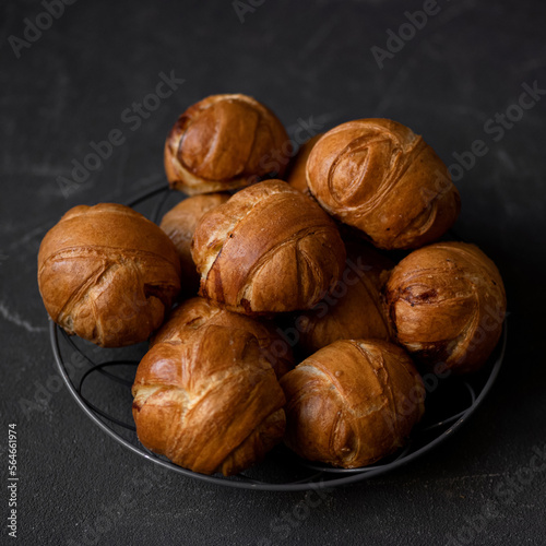 Small round buns. Fresh sweet pastries from yeast dough. Buns for breakfast. Sweets in metal plate on table. Dark background. View from above. Copy space.
