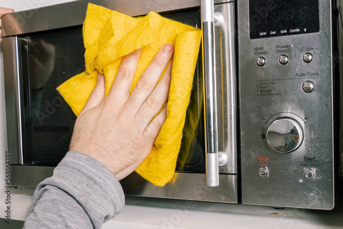 HAND WITH A CLOTH CLEANING THE MICROWAVE