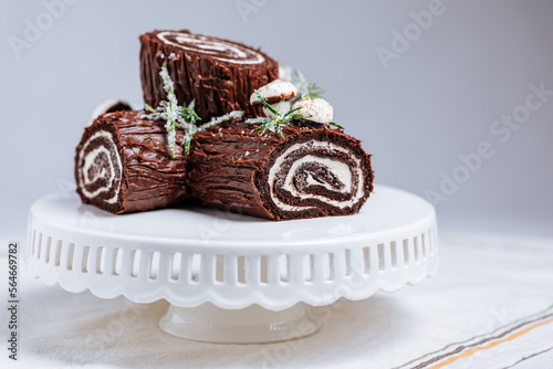 Konstfotografi French dessert called Yule log or bûche de Noël with merengue mushrooms and mint leaves on top of chocolate glazing