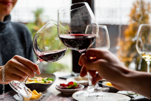 Close up of hands young couple toasting with glasses of red wine at restaurant
