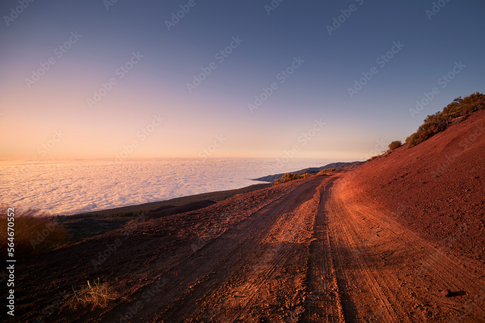 Dirt road in mountains above clouds at beautiful sunset. Tenerife, Canary Islands..