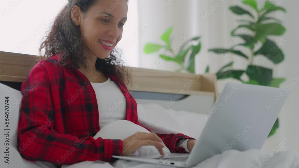 Black african american happy smile carefree woman typing message laptop computer on bed. woman typing on computer browsing surfing internet look at screen having fun chatting in social media. Black african american happy smile carefree woman typing message laptop computer on bed. woman typing on computer browsing surfing internet look at screen having fun chatting in social media.
