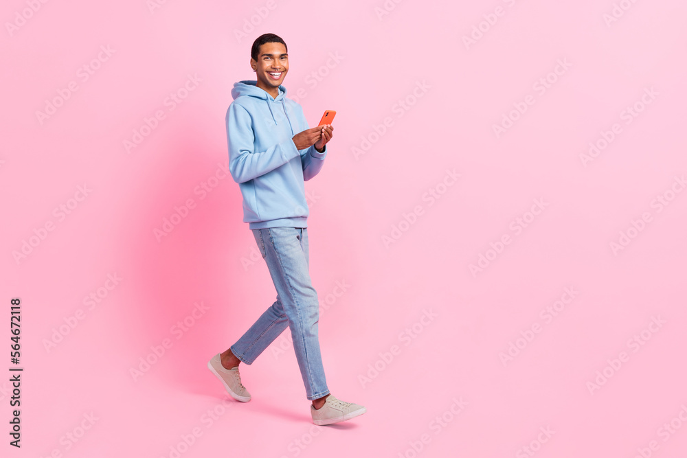 Full length photo of attractive man freelancer wear stylish clothes walk empty space modern device shop isolated on pink color background Full length photo of attractive man freelancer wear stylish clothes walk empty space modern device shop isolated on pink color background