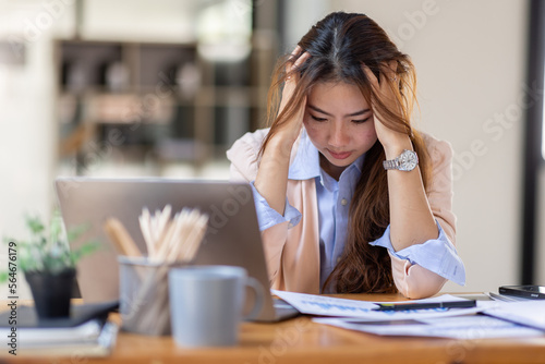 Young business Asian women are stressed while working on laptop, Tired asian businesswoman with headache at office, feeling sick at work copy space in workplace an home office. © David