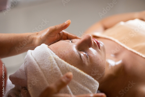 facial mask treatment. Beautiful caucasian woman getting face massage in beauty spa and wellness center. Facial treatment and skin care concept.