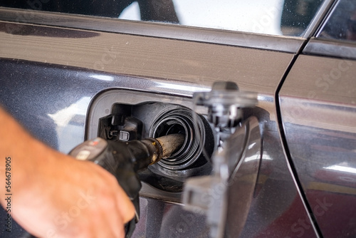 Close up of hand holding gas gun while refueling car with gasoline.