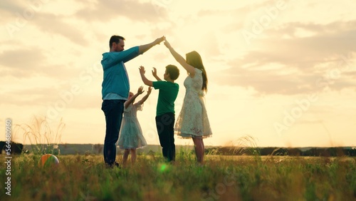 Teamwork happy family shows house with their hands, symbol of safety, comfort for child, sunset. Happy family mother father daughter, son, kid, dream to build house, mortgage for family. Parents child