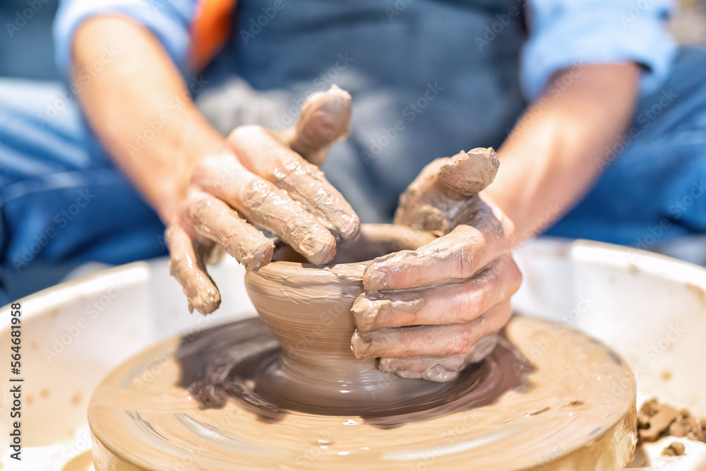 Close up hands make dishes from ceramic clay working on potters wheel traditional pottery craft