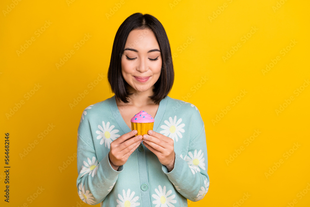 Photo of cheerful lovely girlish cute woman with bob hairdo dressed blue pullover fingers hold cake isolated on yellow color background Photo of cheerful lovely girlish cute woman with bob hairdo dressed blue pullover fingers hold cake isolated on yellow color background