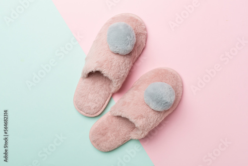 Soft pink slippers on color background, top view