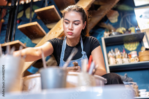 Women learn to make clay pot on potters wheel making ceramic clay objects in pottery workshop