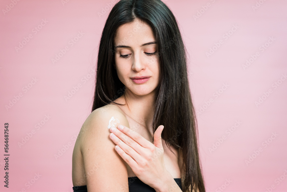 Attractive woman touching clean skin and looking at camera applying cream Attractive woman touching clean skin and looking at camera applying cream