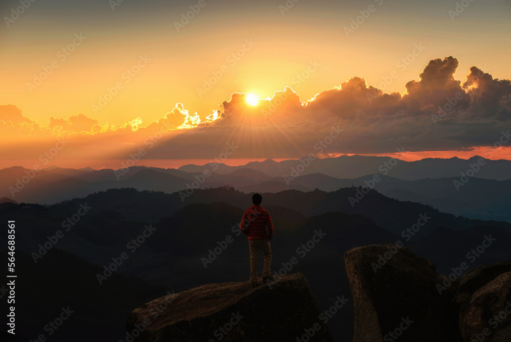 Hiker man standing and looking the view on top of mountain during sunset in tropical rainforest at national park