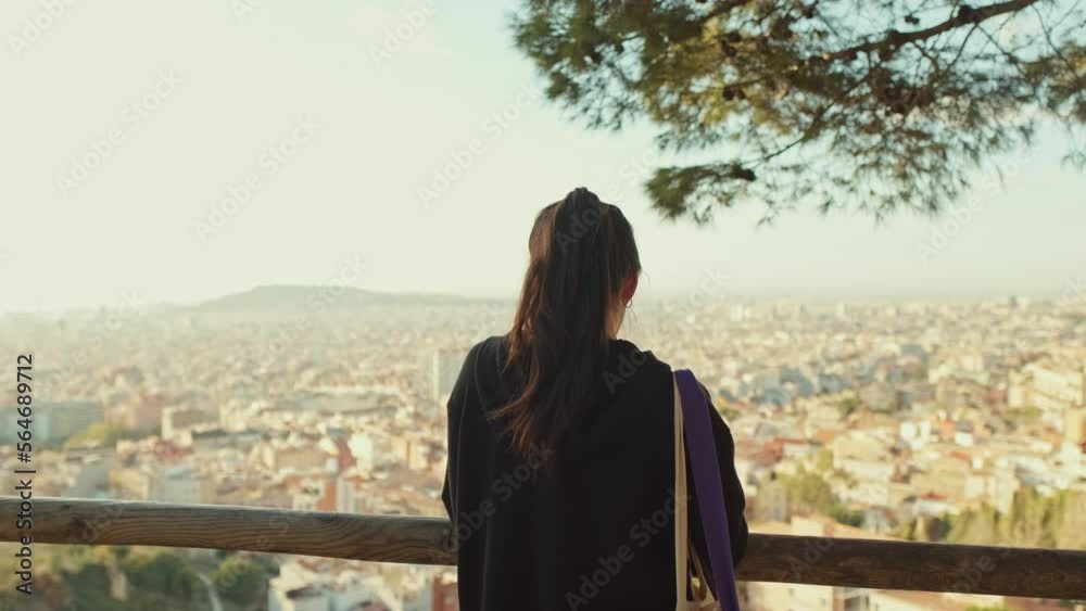 Young woman stands on viewing platform and looks around. Back view Young woman stands on viewing platform and looks around. Back view